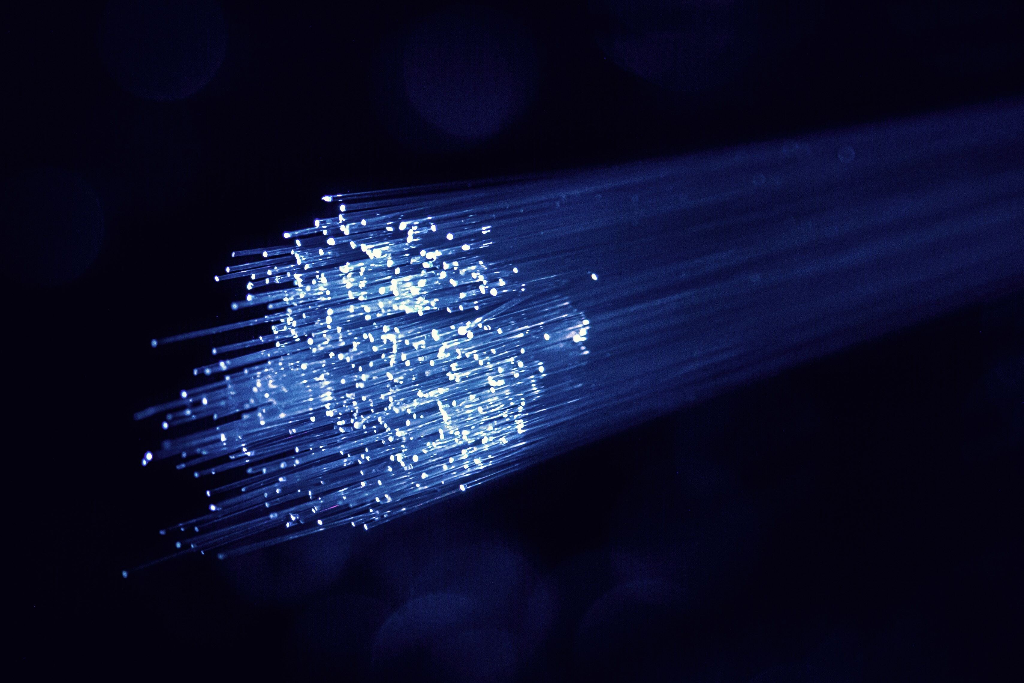 A magnified view of Fiber-Optic cables with data light emitting from them in a dark background as Glo Fiber technicians prepare to install them.